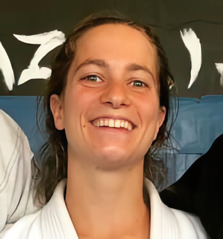 Coach Abbey Rae Rester smiling in a white gi at the Jiu-Jitsu dojo