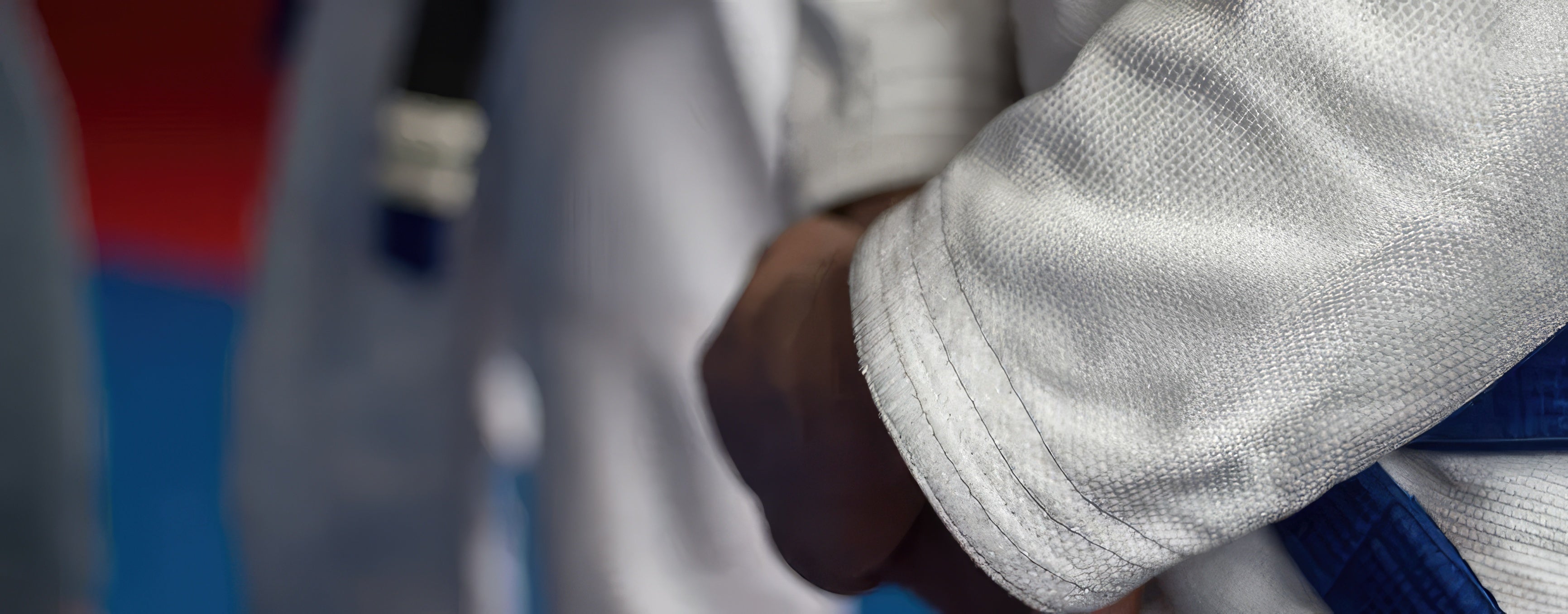 Detail of a white Brazilian Jiu-Jitsu gi with a blue belt